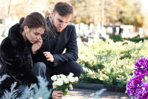 Couple Putting Flowers On Grave (1)