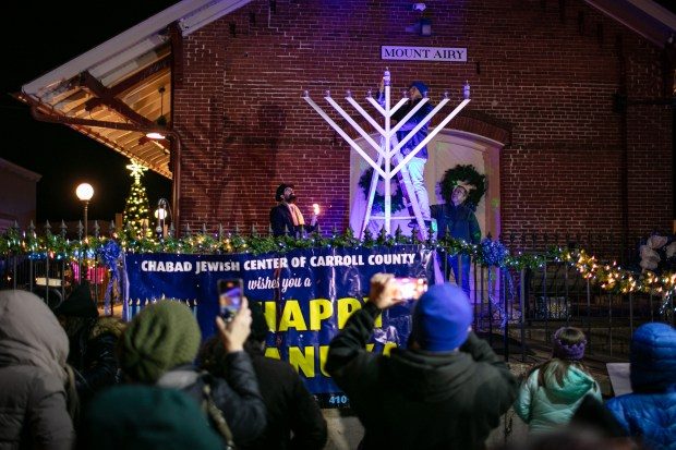 Dec. 7, 2023: Mt. Airy Mayor Larry Hushour, center, lights the menorah candle with Rabbi Sholly Cohen, left.The annual Chanukah Menorah lighting on Main Street in Mt. Airy, co-hosted by the Chabad Jewish Center of Carroll County. (Nate Pesce/ for Carroll County Times)