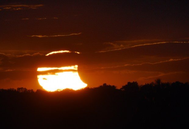 The sun breaks through heavy cloudcover revealing a partial solar eclipse at sunset on Oct. 23, 2014.