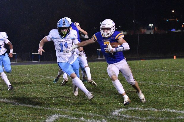 Liberty's Kevin Poole runs the ball in front of Westminstter's Conner Hereth during a football game at Liberty High School on October 20, 2023.