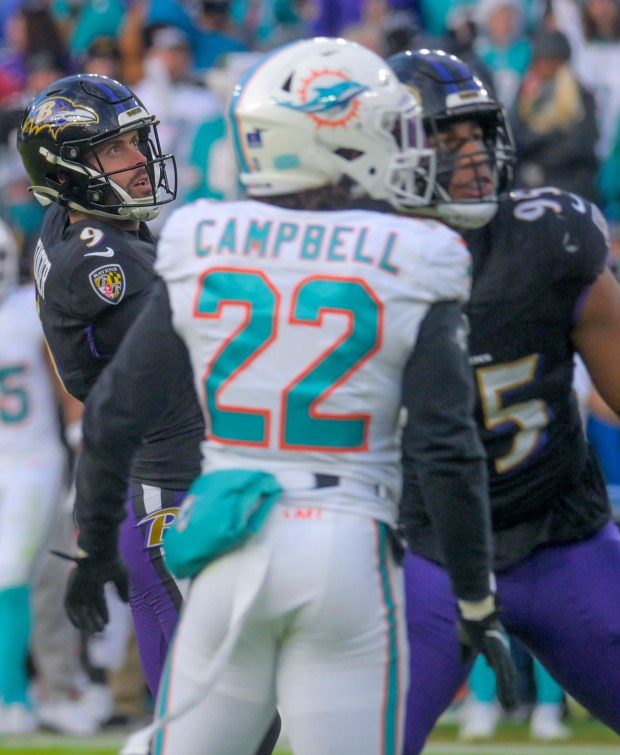 Baltimore Ravens kicker Justin Tucker adds the point after try to the board as outside linebacker Tavius Robinson and Miami Dolphins defensive back Elijah Campbell watch during the fourth quarter of an AFC matchup of NFL football in Baltimore. The Ravens became the AFC North champions, securing home field advantage throughout the playoffs with their 56-19 drubbing of Miami. (Karl Merton Ferron/Baltimore Sun Staff)